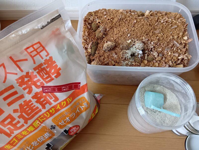 猫フンとおがくずが入ったタッパーの手前に生ごみ促進剤が並べてある様子